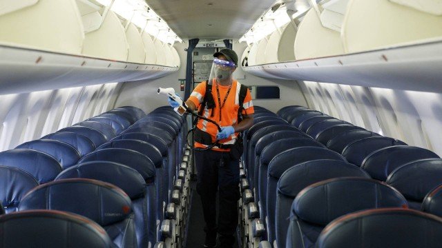 Funcionário de companhia aérea durante trabalho de desinfecção da cabine